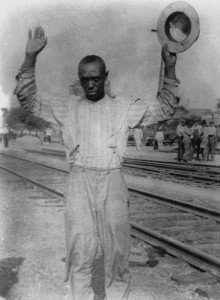 A black man being detained during the riot, while white men watch from across the tracks. (Courtesy of the Tulsa Historical Society.)