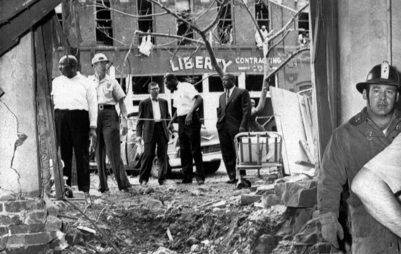 In this Sept. 15, 1963 file photo, emergency workers and others stand around a large crater from a bomb which killed four black girls in the Sixteenth Street Baptist Church in Birmingham, Ala. The windows of the building across the street in the background were also blown out. (AP Photo)