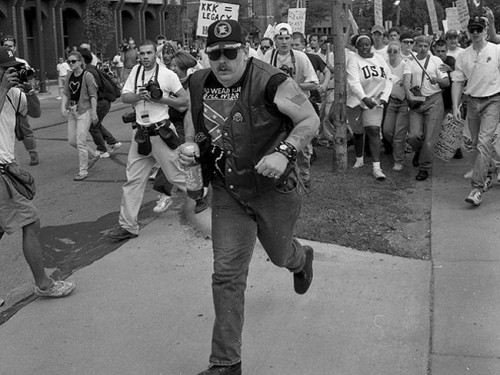 [UNVERIFIED CONTENT] June 22, 1996. A dozen members of a self-anointed and unwelcome KKK group came to Ann Arbor to hold a thumb-in-your-eye rally at City Hall. A protest group, the National Women's Rights Organizations Coalition (NWROC) formed to oppose them. After the rage had been mounting for awhile, this simpleminded redneck wandered up, wearing a Confederate-flag T-shirt and drinking a bottle of Lipton tea. The crowd tore off after him, he fell, and the mob pounced, striking for blood. Keshia Thomas, horrified, threw herself over him to stave off the angry blows. Moments earlier, Thomas, 18, had been in the NWROC group, shouting at the KKK. It was a heroic and passionate moment in a crazy afternoon, well captured in these photographs.
In a story in People Magazine, Thomas was quoted as saying, &quot;You don't beat a man up because he doesn't believe the same things you do. He's still somebody's child.&quot;
The guy never dropped his tea bottle . . . .
(He was later identified as one Albert McKeel, Jr.)