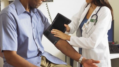 A doctor checks a Black patient's blood pressure