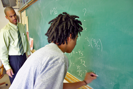 Black student writing on chalkboard