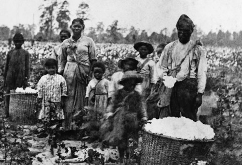 Slave Family: A slave family standing next to baskets of recently-picked cotton near Savannah, Georgia in the 1860s. (Photo Credit: Bettmann/CORBIS)