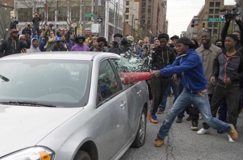 Allan Bullock breaks the window of a police car during protests in Baltimore on April 25, 2015.