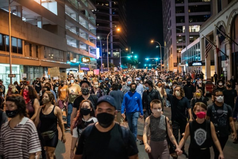 People walk down street in Austin after vigil