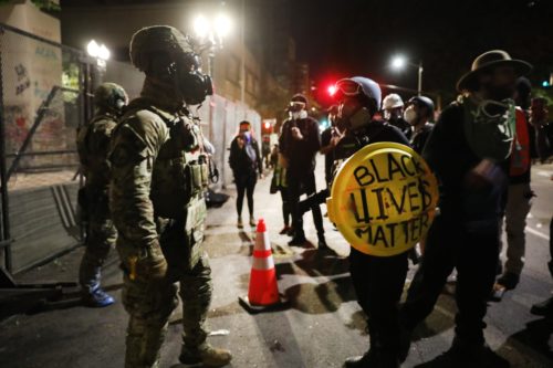 Federal police confront protesters in downtown Portland as the city experiences another night of unrest on July 26, 2020 in Portland. BY SPENCER PLATT/GETTY IMAGES