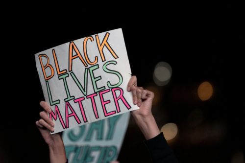 Screen Shot 2020-09-25 at 11.59.18 AM A protester holds up a Black Lives Matter sign