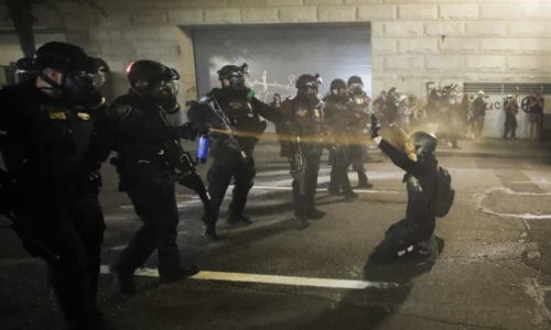 3000 Police in riot gear spray tear gas in the face of a single kneeling protester