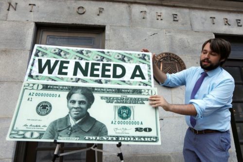 Man holding a big Harriet Tubman $20 dollar bill