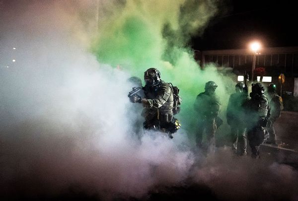 Federal officers walk through tear gas