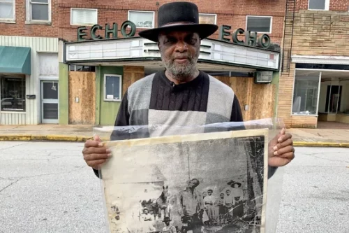 The Rev. David Kennedy stands outside the Echo Theater in Laurens, S.C., holding a photo of his great-great uncle's lynching. (Sarah Black Morgan / AP)