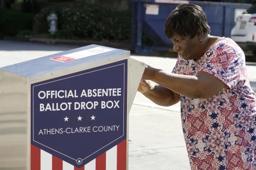 A voter drops a ballot off in Athens, Ga., on Oct. 19, 2020. (John Bazemore / AP file)