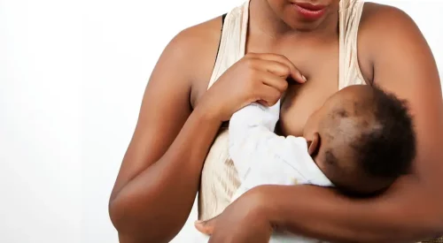 A Black woman holds an infant (Kingspirit Image Room/Shutterstock)