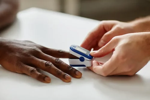 94ef2ae3e0230ef6458cf85c09a5ed96 A pulse oximeter is placed on a black person's finger (SeventyFour/Shutterstock)