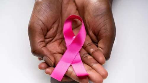 image Black hands hold a breast cancer awareness ribbon (Adobe Stock)