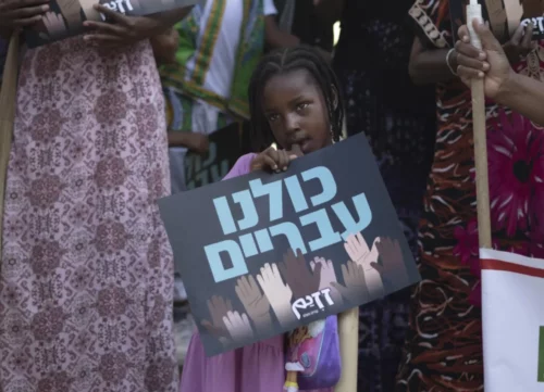 A child from the Hebrew Israelite community holds a placard that reads "We are all Hebrew," at a rally outside of the District Court in Beersheba, Israel,  in July 2023.  (AP Photo/Maya Alleruzzo)