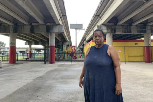 Amy Stelly, an artist, urban designer, and community activist, stands beneath the Claiborne Expressway on July 18. Stelly, who lives nearby, is working with Louisiana State University on an Environmental Protection Agency study of the noise and air pollution from the highway, and still supports moving this stretch of Interstate 10 away from the historically Black community. (DREW HAWKINS/GULF STATES NEWSROOM)