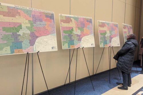 An attendee at a redistricting public hearing in Detroit considers several options for new metro Detroit state House districts. Seven existing House districts were scrapped by a federal court, where judges determined the commission improperly used racial data to draw maps. (Bridge photo by Lauren Gibbons)