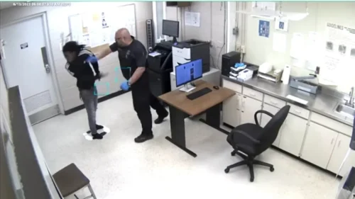 Footage from video captured now-former Warren Police officer Matthew Rodriguez (right) punching Jaquwan Smith (left), a man under arrest, in the city jail's fingerprinting area, then slamming his head against the floor and pushing him into a cell. (Photo: Screenshot/YouTube.com/Detroit Free Press)