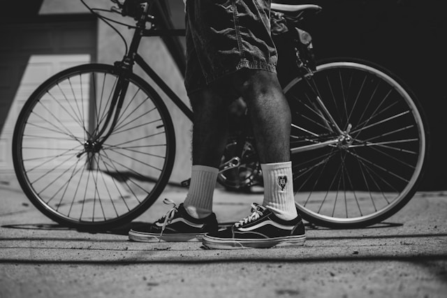 A Black man's legs and feet in front of a bike