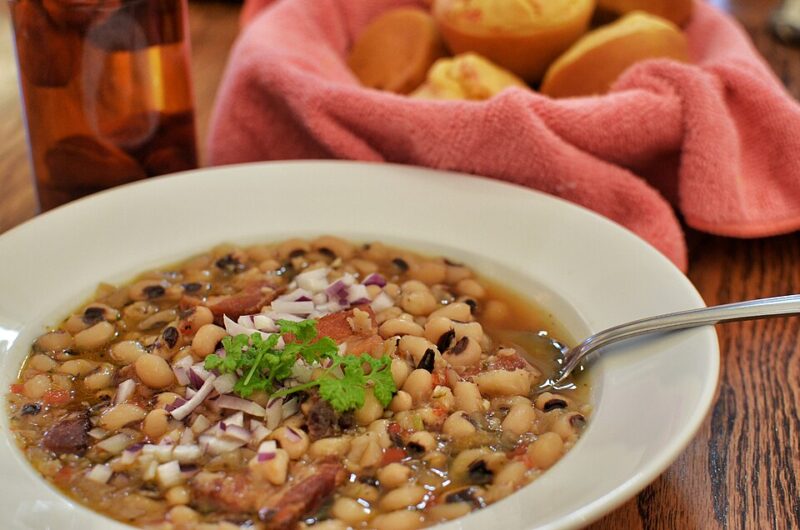A bowl containing black eyed peas and a spoon